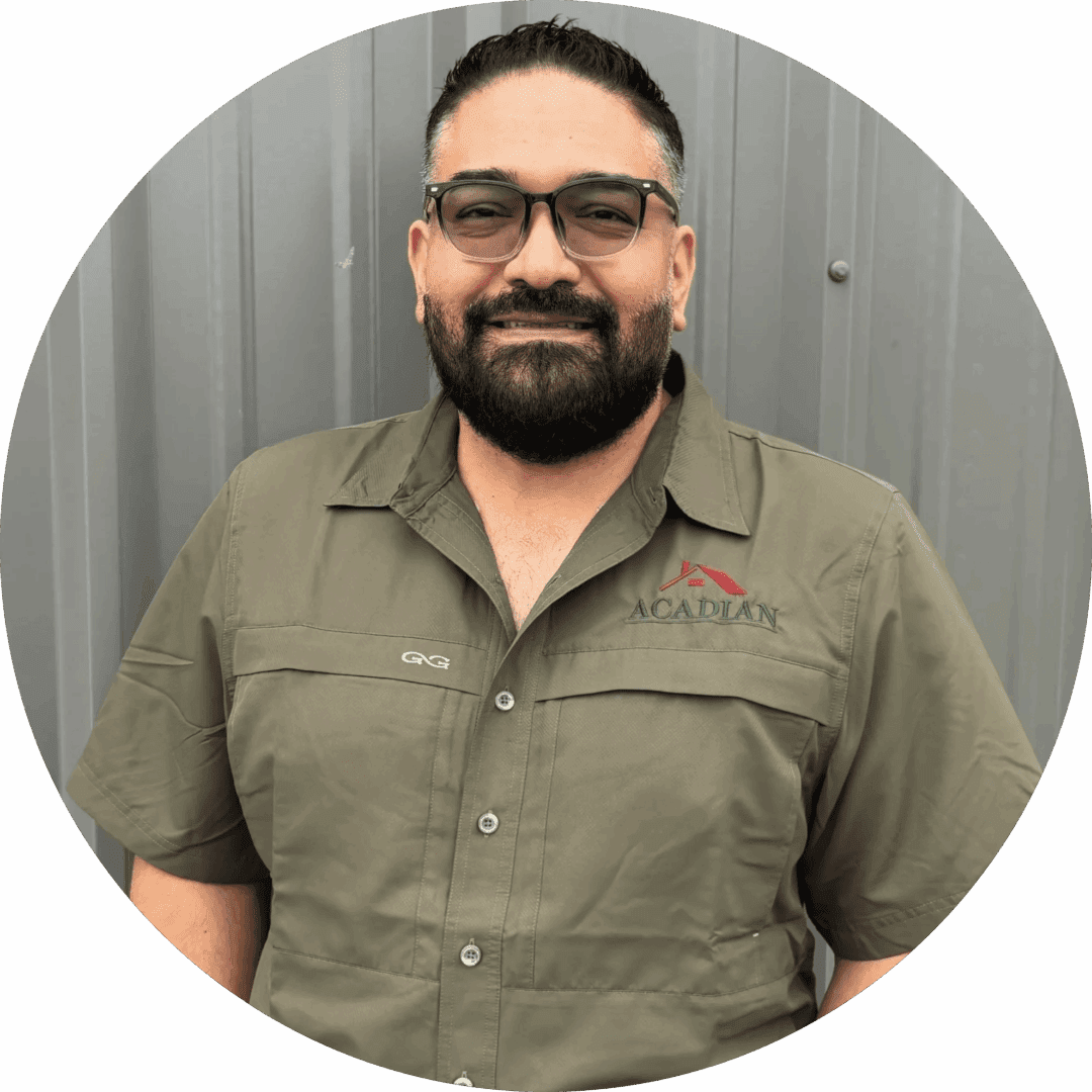 Man in green shirt, standing, smiling outdoors.